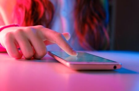72% of US teens have used AI companions, study finds person touching a smartphone laying on a table.