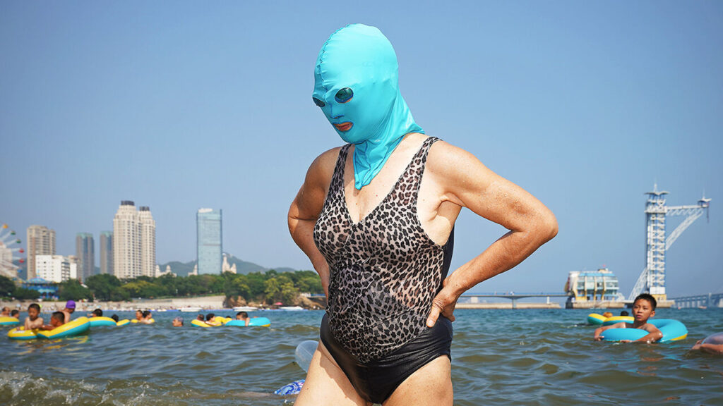 A woman wears a facekini on a beach.