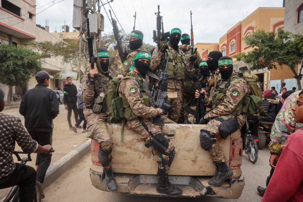 Hamas fighters patrol a street before they hand over three Israeli hostages to a Red Cross team in Deir el-Balah, central Gaza, on Feb. 8.
