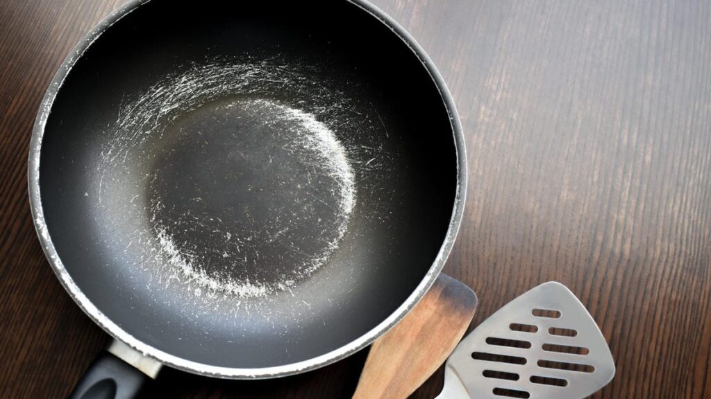 A worn out nonstick skillet with spatulas to the right.
