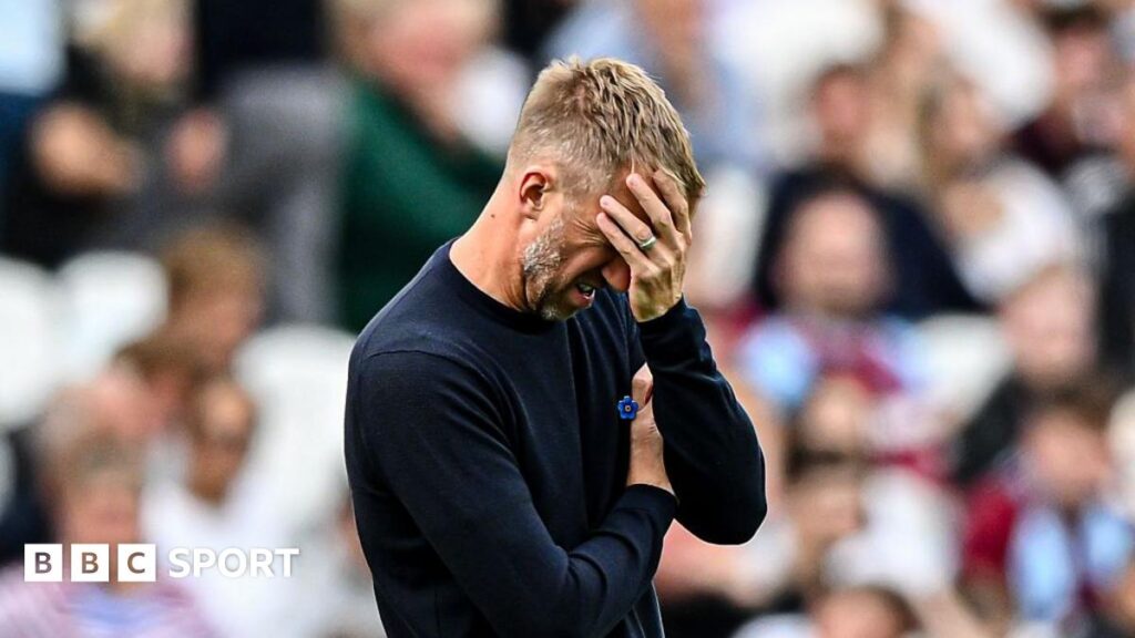 Graham Potter with a raised left hand partly covering his face, looking frustrated