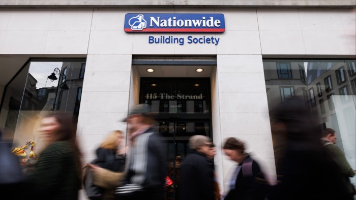 Cutting cash Isa limit could lead to 60,000 fewer mortgages a year People walk past the entrance of a Nationwide Building Society branch, with the company sign clearly visible above the door.