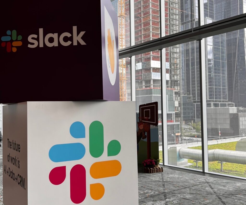 Unthread has a plan for cleaning up Slack and will show off its tech at TechCrunch Disrupt 2025 Cubes with Slack name and logo stacked on one another with city view in background.