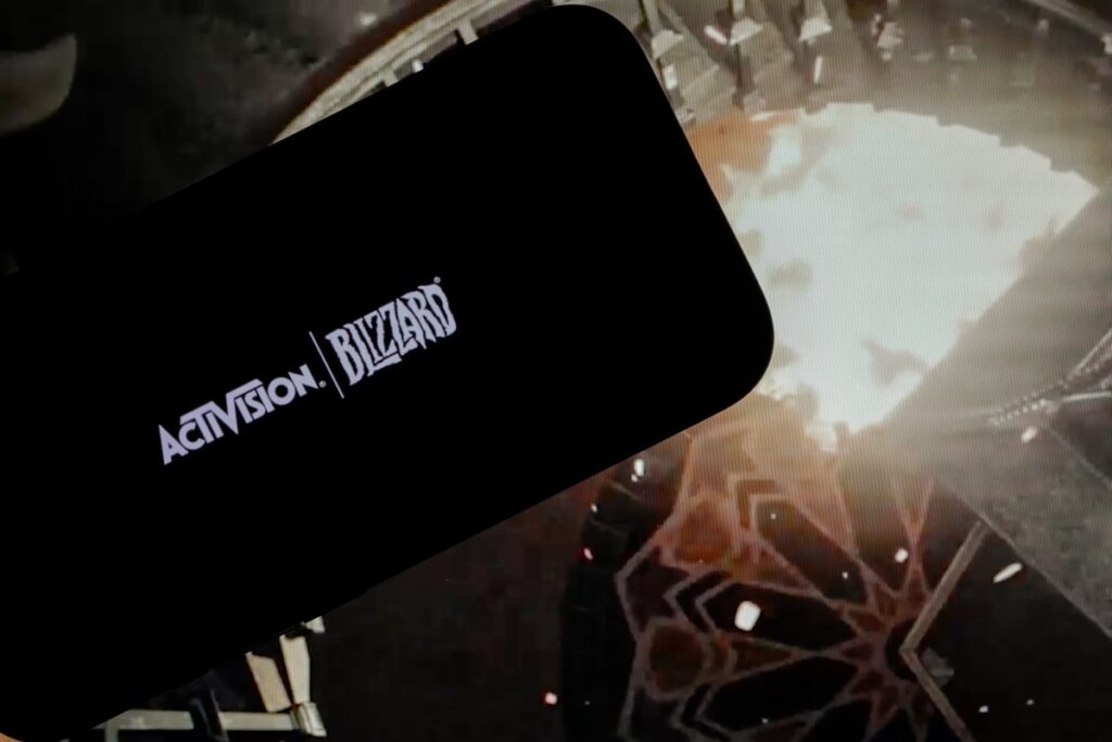 logo of ''Activision Blizzard'' is displayed on a mobile phone screen in front of a computer